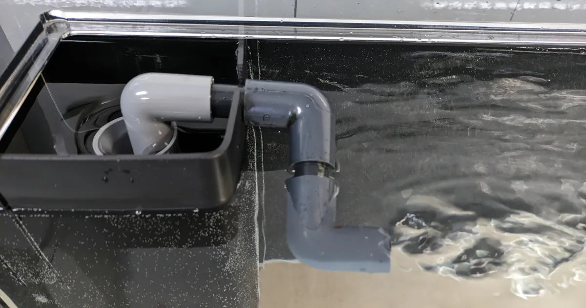 水槽の角に設置した黒いコーナーカバーと内部配管の実例写真