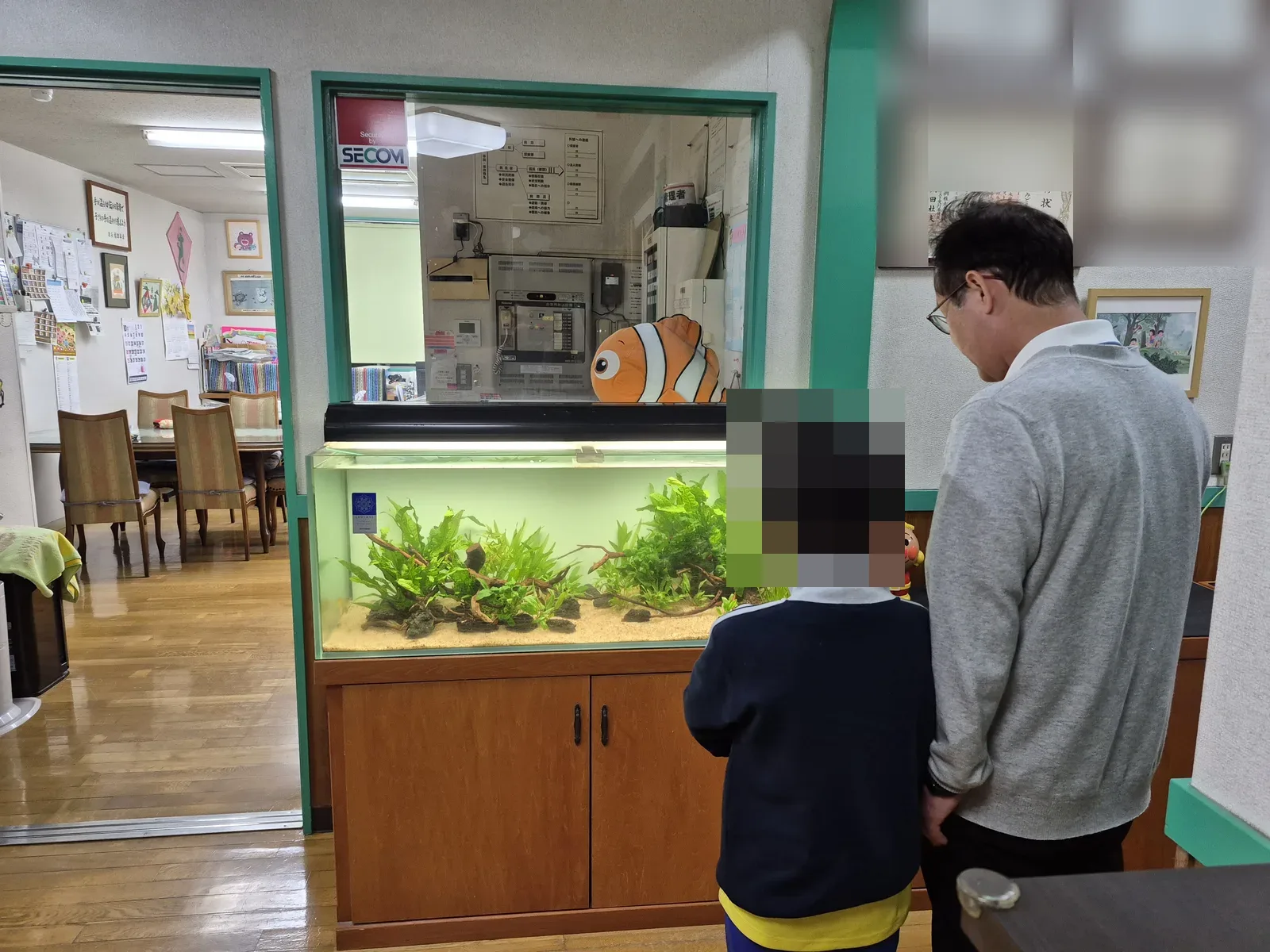 園長先生とお子さんが並んで、水草水槽の中をのぞきこんでいる様子